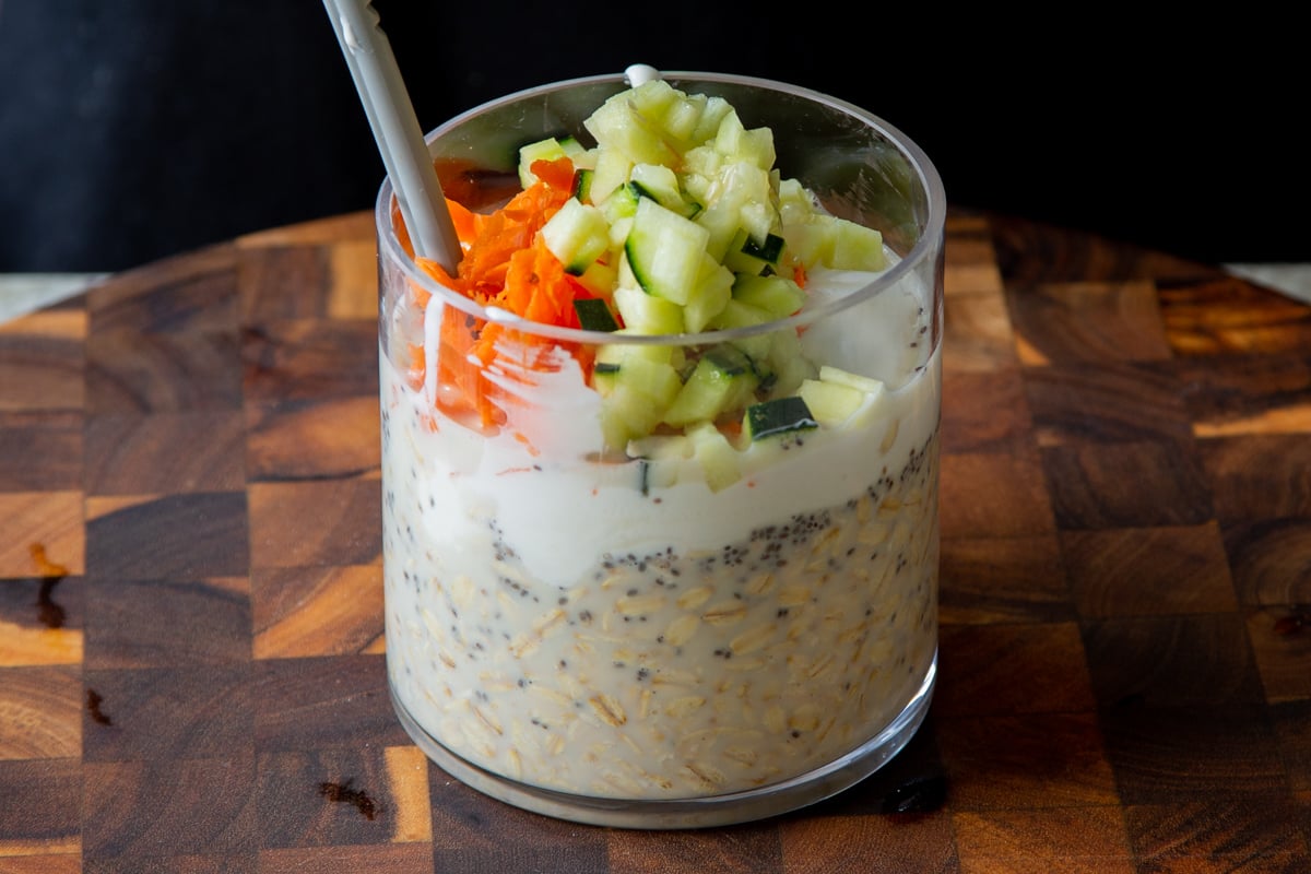 adding yogurt, carrots, and cucumber to the soaked oats and chia seeds