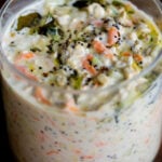 savory overnight oats topped with Indian spiced tempering in a glass jar, after stirring the tempering in a little bit