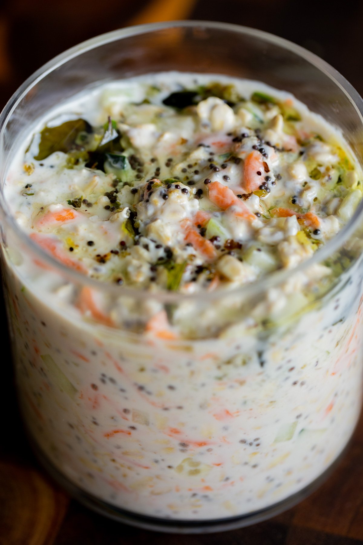 savory overnight oats topped with Indian spiced tempering in a glass jar, after stirring the tempering in a little bit