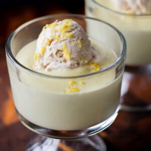 cups of vegan lemon pudding topped with vanilla ice cream on a wooden table