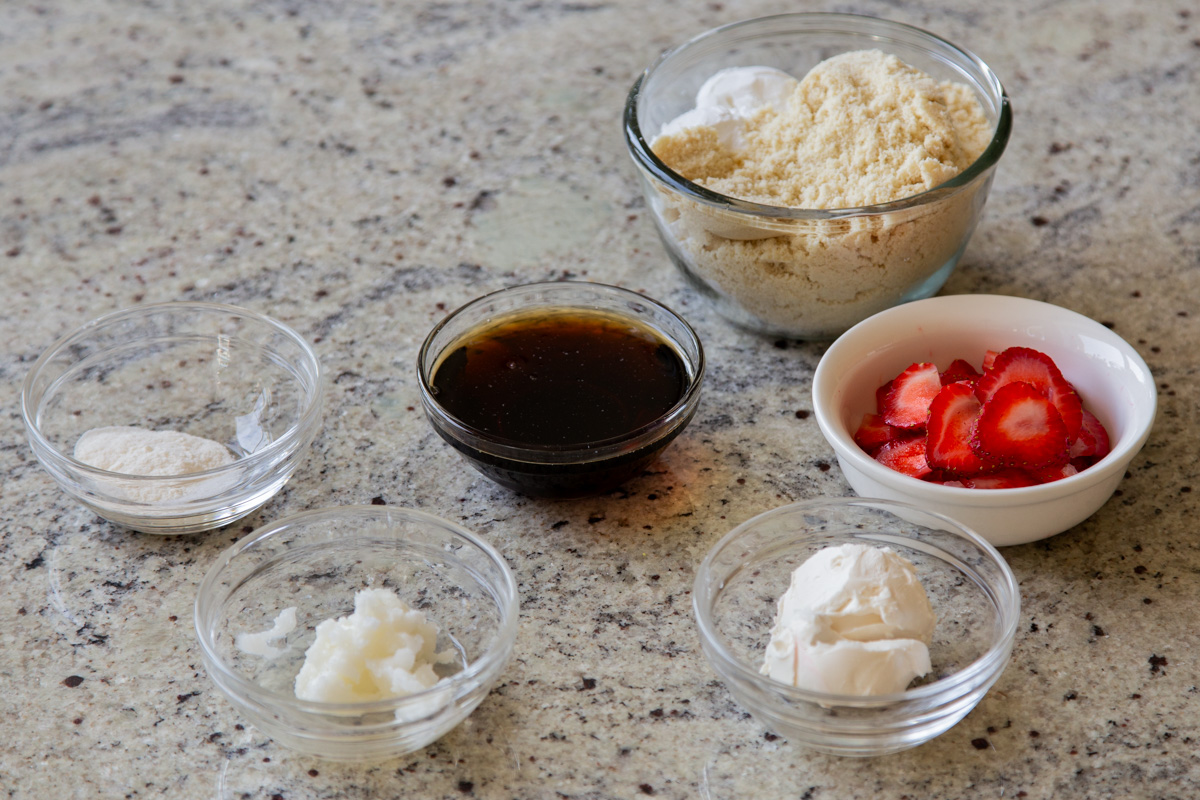 almond flour, strawberries, and other cookie ingredients in bowls on a kitchen counter