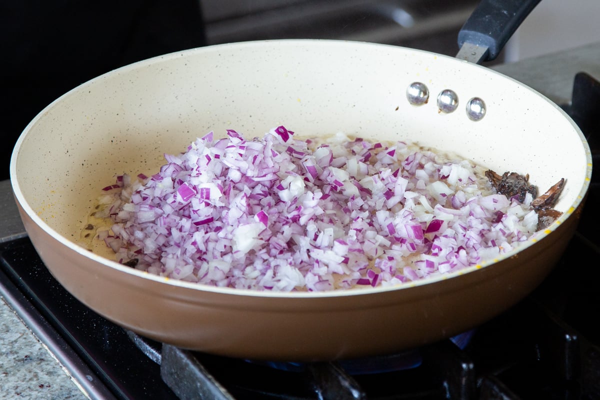 adding onion to the pan of toasted spices