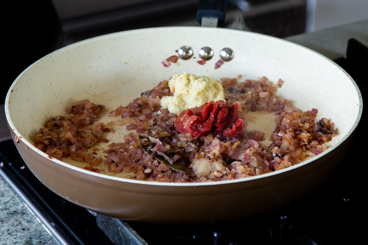 adding ginger-garlic paste and tomato paste to the cooked onions