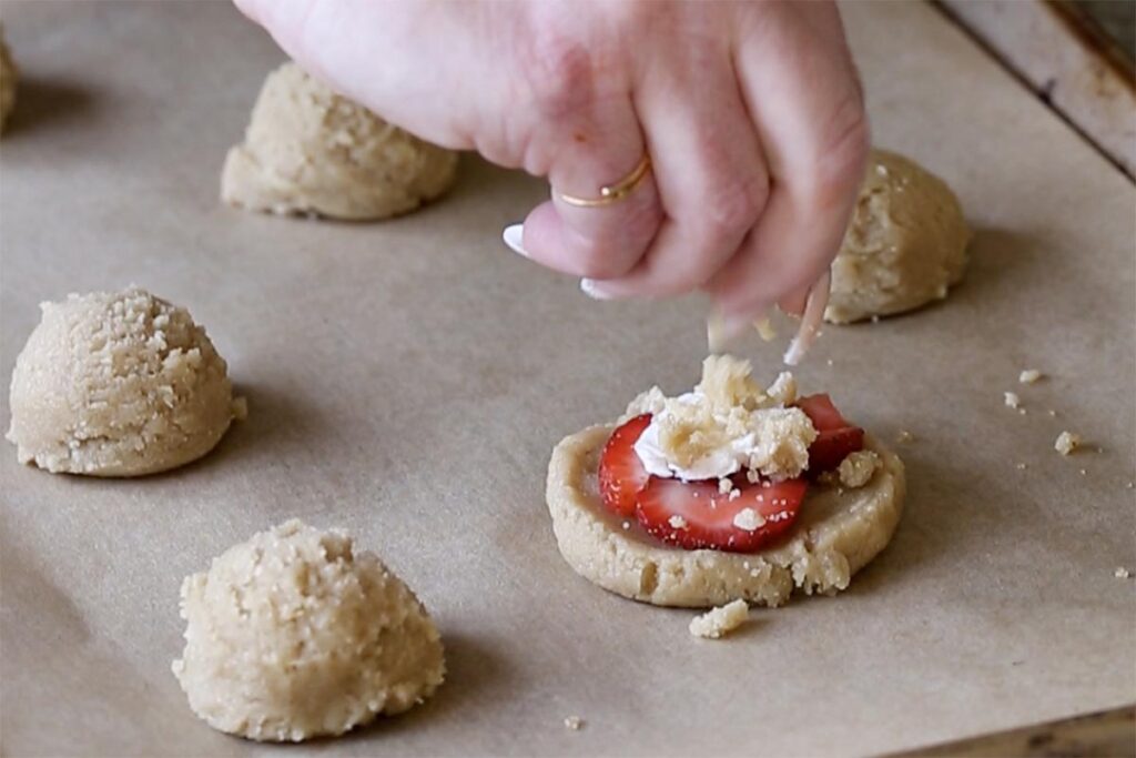 adding the crumble topping to the strawberry cheesecake cookie
