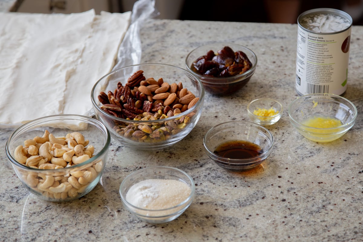 phyllo sheets, nuts, and other baklava cheesecake ingredients in bowls on the kitchen counter