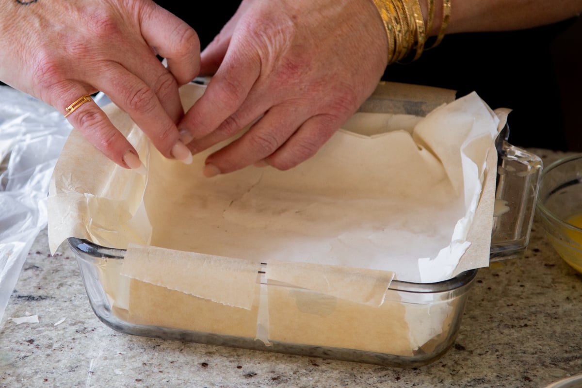 adding the buttered phyllo sheets to the baking pan