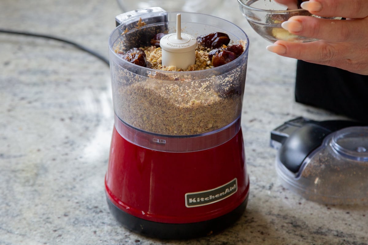 adding dates to the food processor with the processed nuts