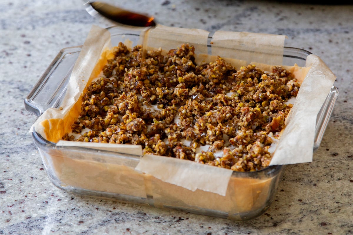 drizzling maple syrup over the baklava cheesecake, before freezing