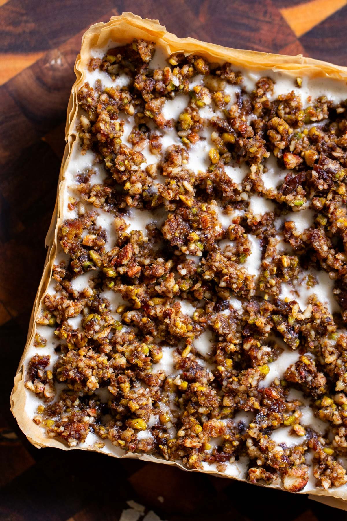 baklava cheesecake on a wooden cutting board, before slicing