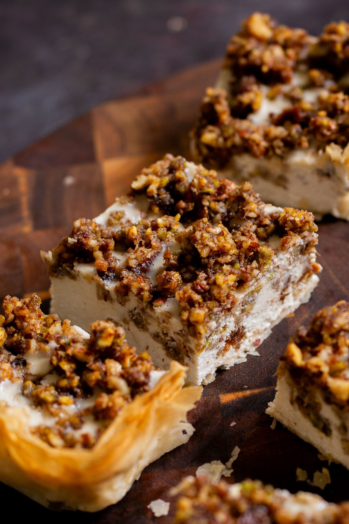 side view of baklava cheesecake on a wooden cutting board