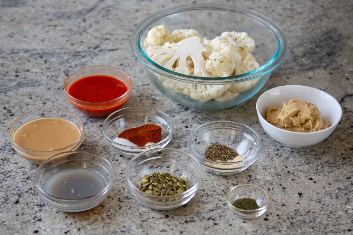 cauliflower, harissa paste, and other ingredients in bowls on a kitchen counter