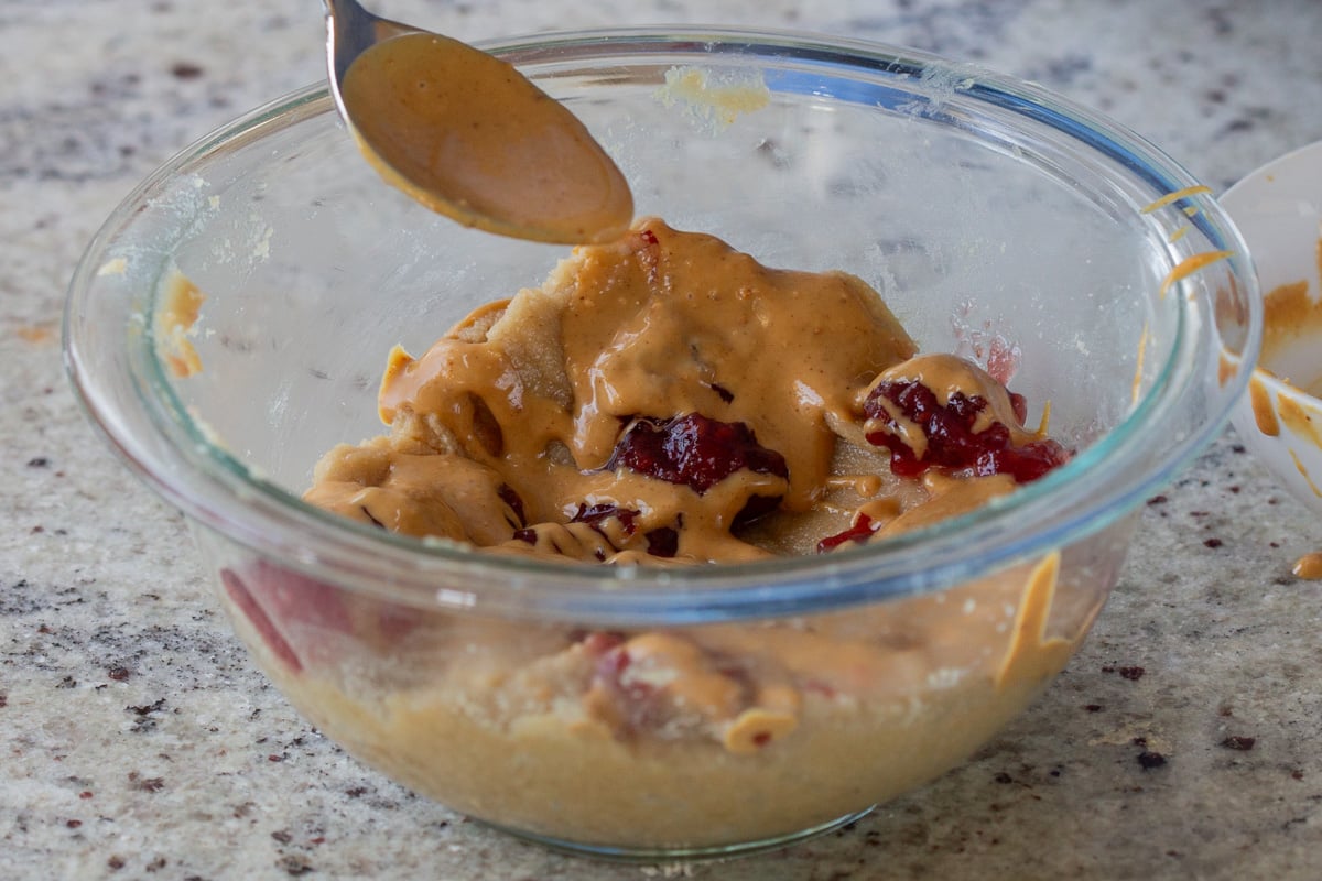 adding peanut butter and jelly to the almond flour cookie dough