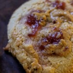 extreme close-up of a gluten-free peanut butter and jelly cookie on a wooden cutting board