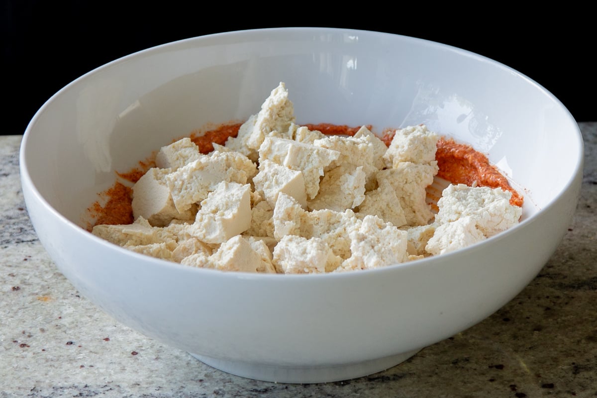 adding tofu to the bowl with the seasoned yogurt mixture