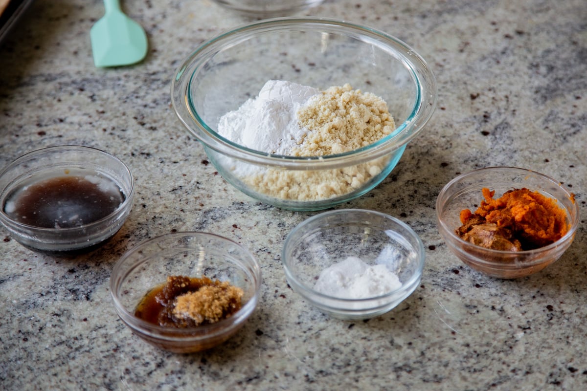 almond flour, tapioca starch, and other cookie ingredients in bowls on a kitchen counter
