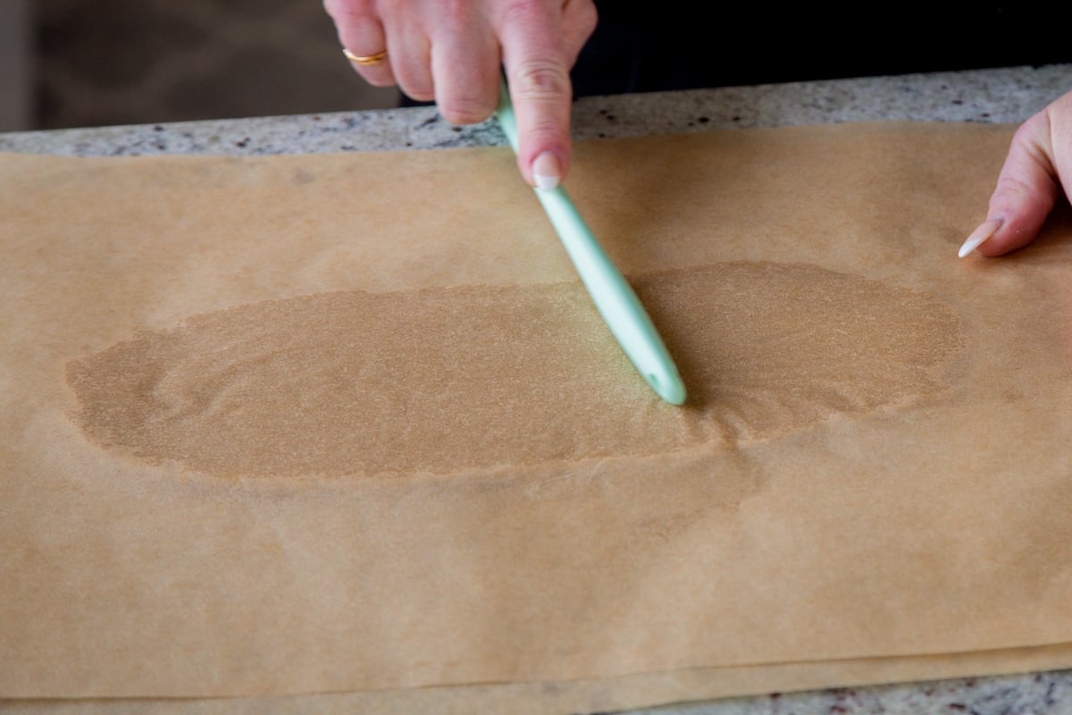 rolling out almond flour cookie dough between 2 pieces of parchment paper