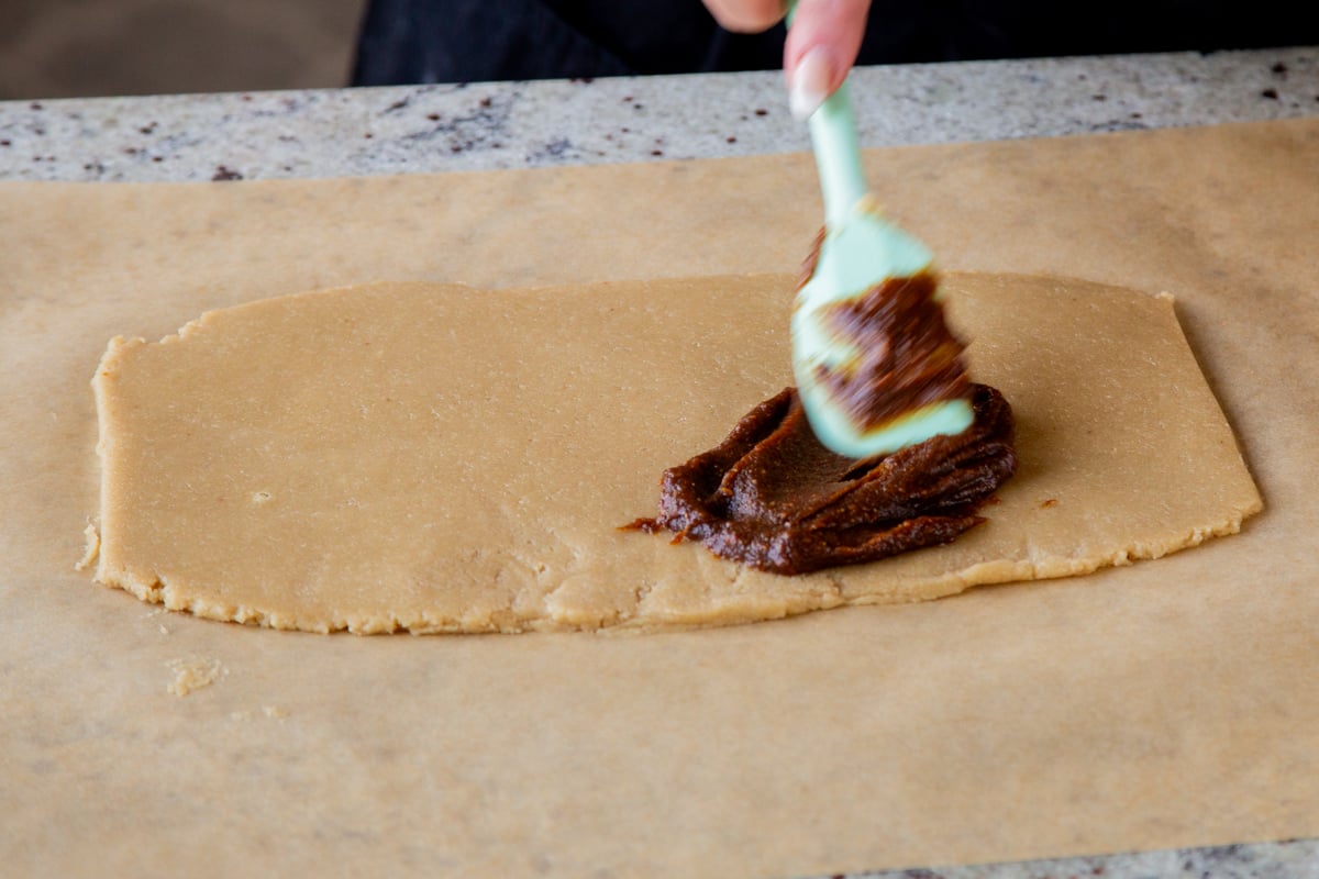 spreading the pumpkin pie spice mixture onto the rolled out almond flour cookie dough