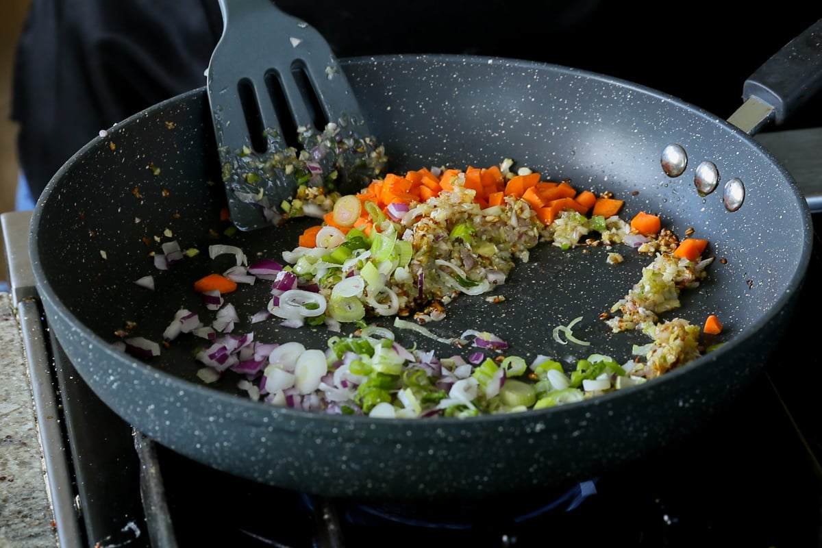 adding carrots and onions to the cooked aromatics in the pan