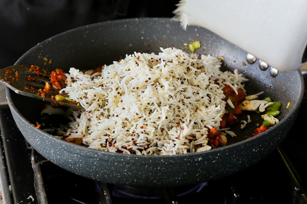 adding rice mixture to the Schezwan sauce and veggies in the pan