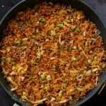 Schezwan fried rice in the pan with green onions for garnish