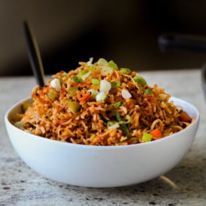 Schezwan fried rice in a bowl with green onions for garnish
