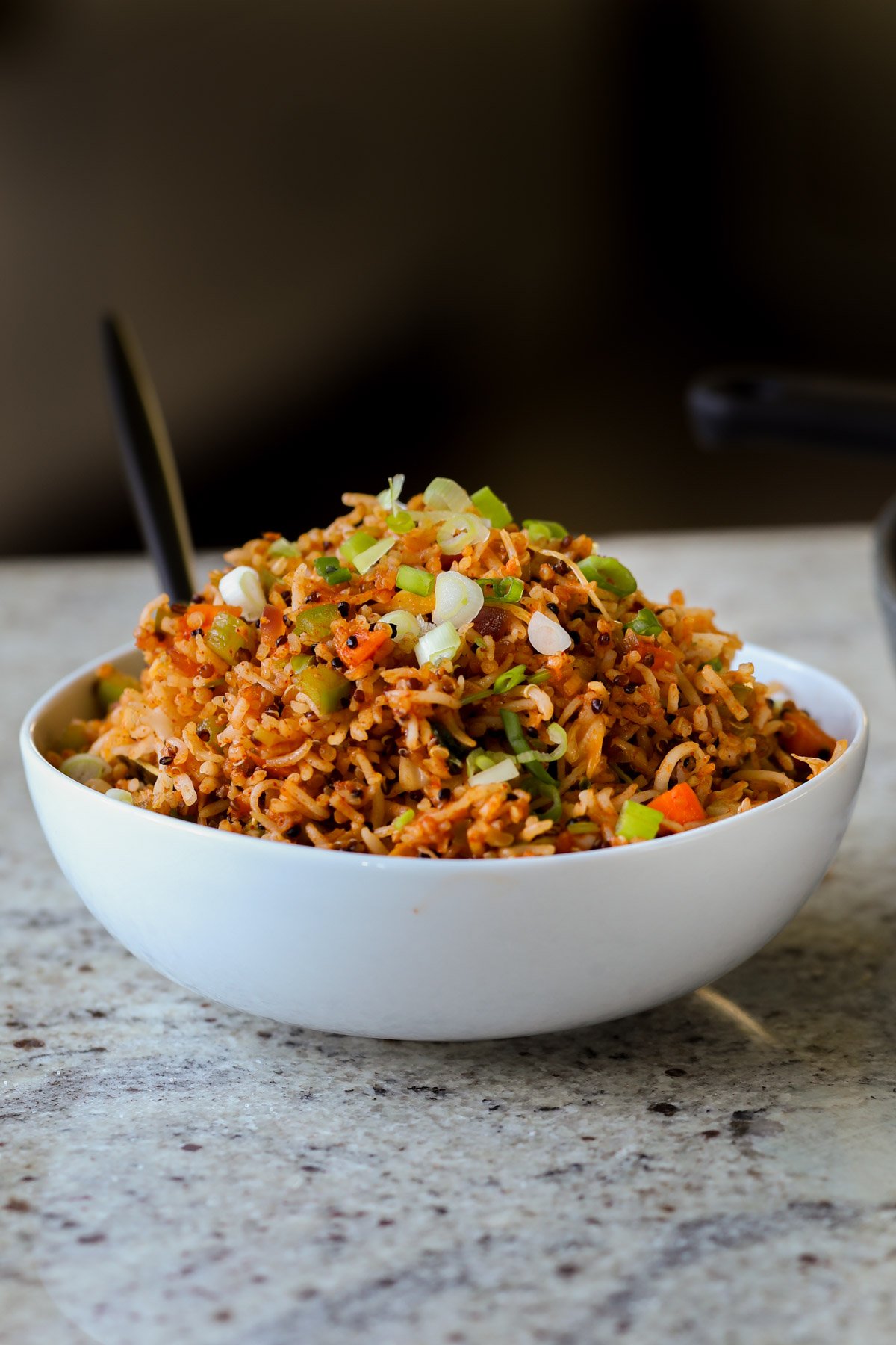 Schezwan fried rice in a bowl with green onions for garnish