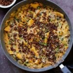 smoky skillet lasagna in the pan, topped with crispy lentils and fresh herbs