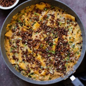 smoky skillet lasagna in the pan, topped with crispy lentils and fresh herbs
