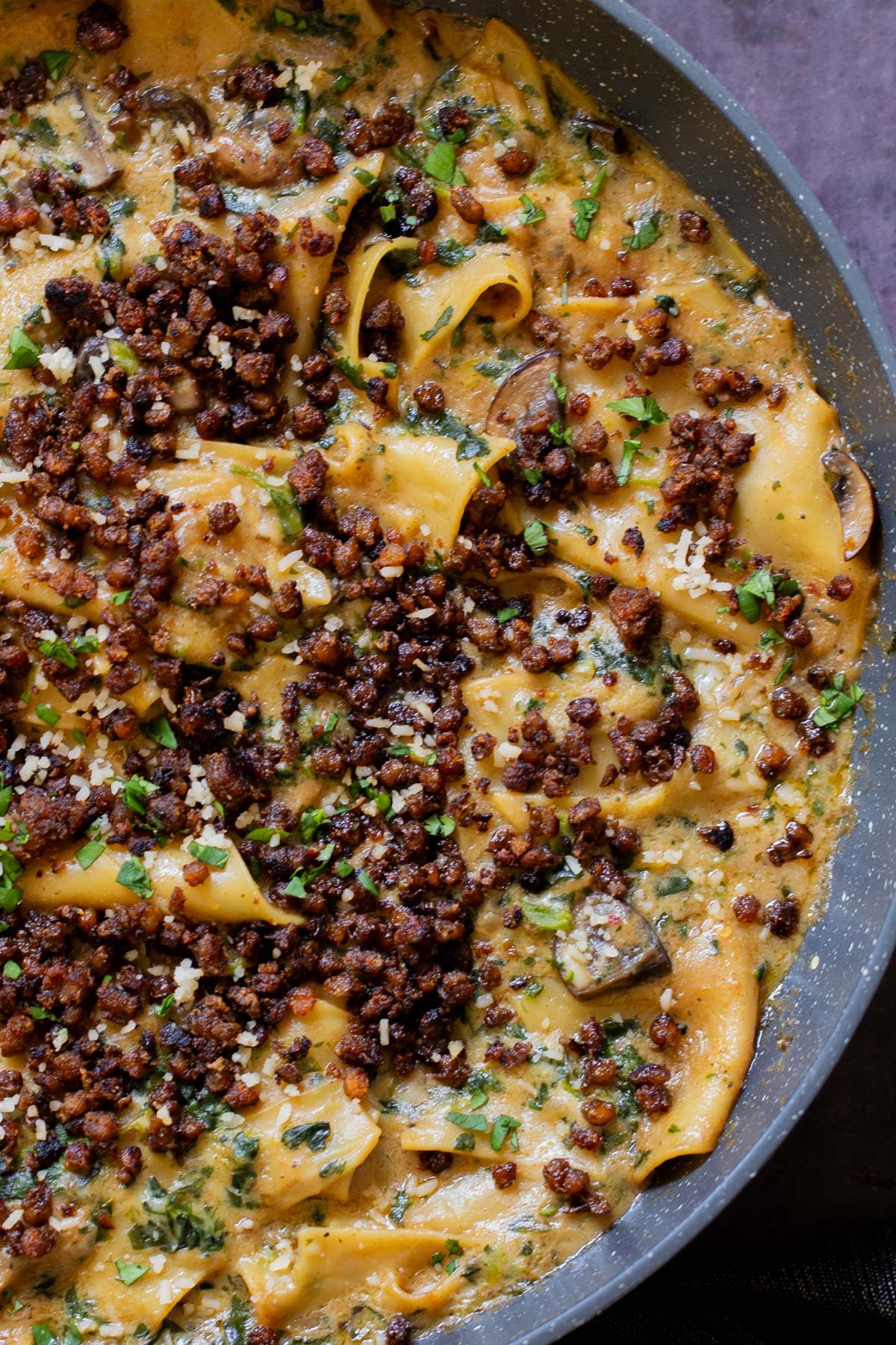 close-up of smoky skillet lasagna in the pan, topped with crispy lentils and fresh herbs