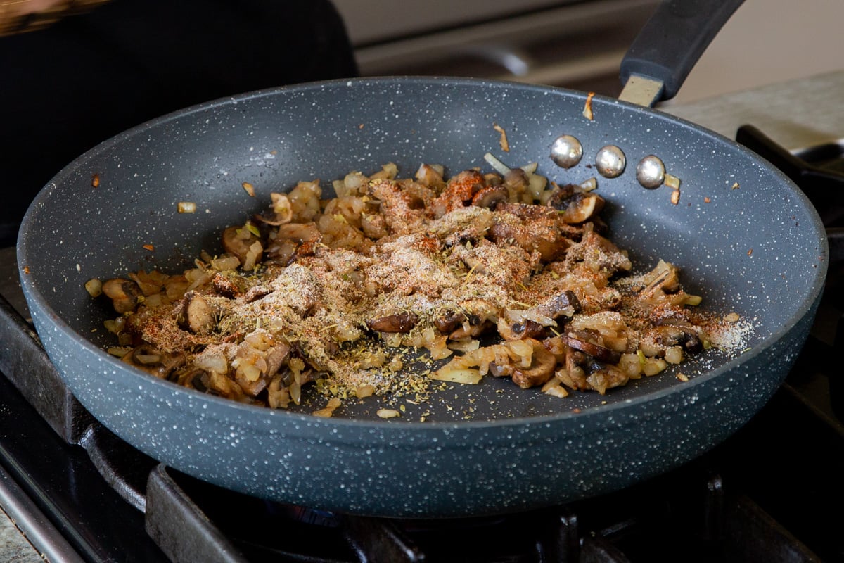 onion and mushrooms in the pan, after cooking, with dried spices added