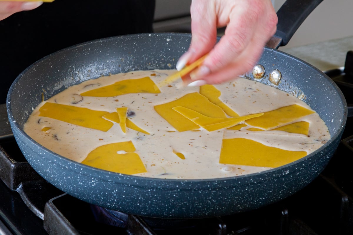 adding broken up lasagna noodles to the sauce