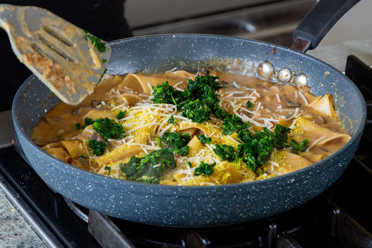 adding spinach to the smoky skillet lasagna