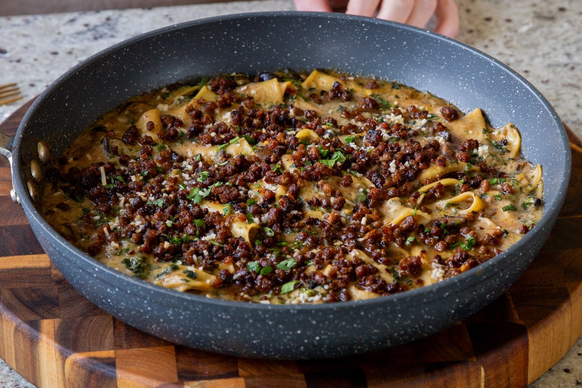 smoky skillet lasagna in the pan, topped with crispy lentils and fresh herbs