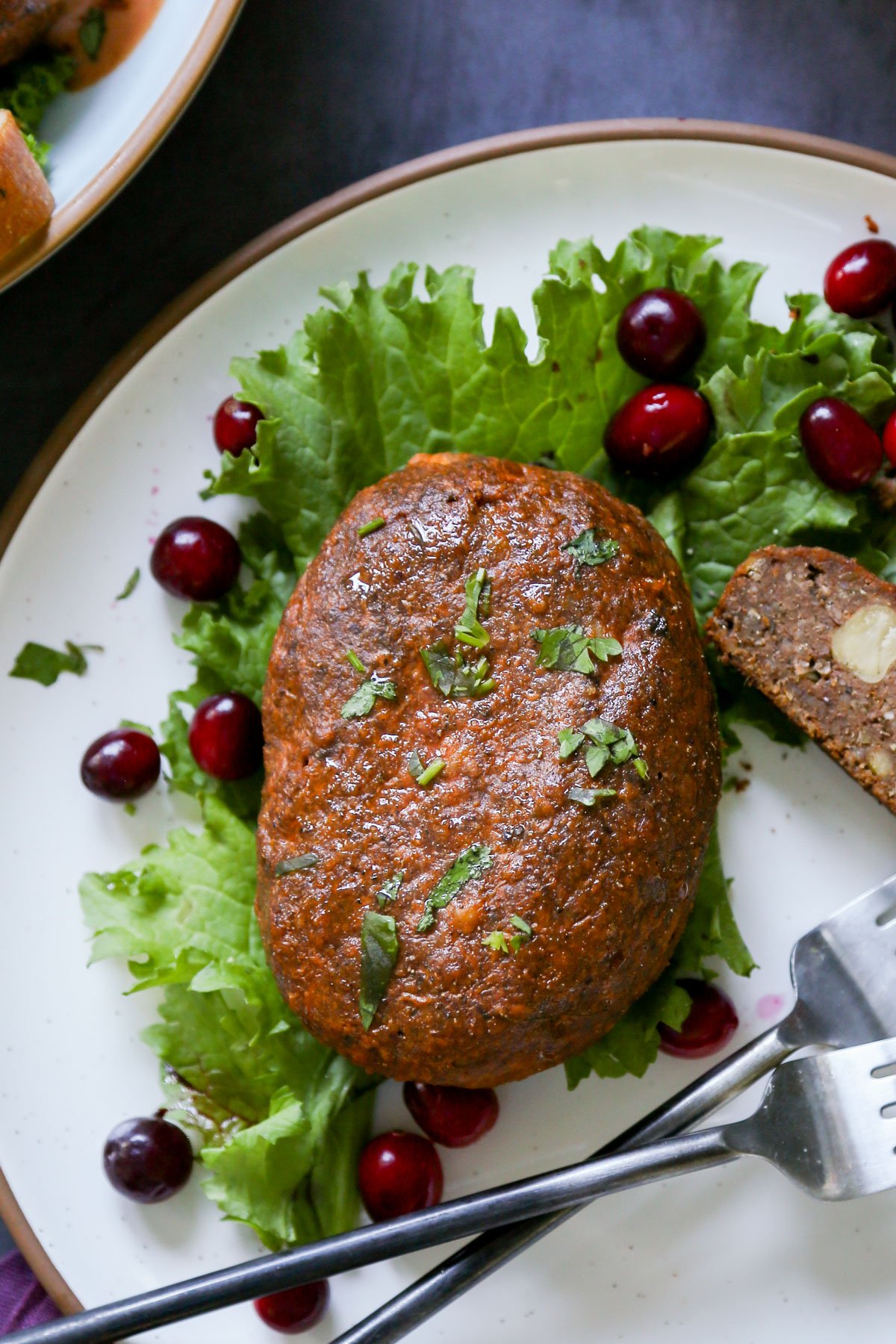 close-up of a chickpea loaf on a plate with lettuce and cranberries