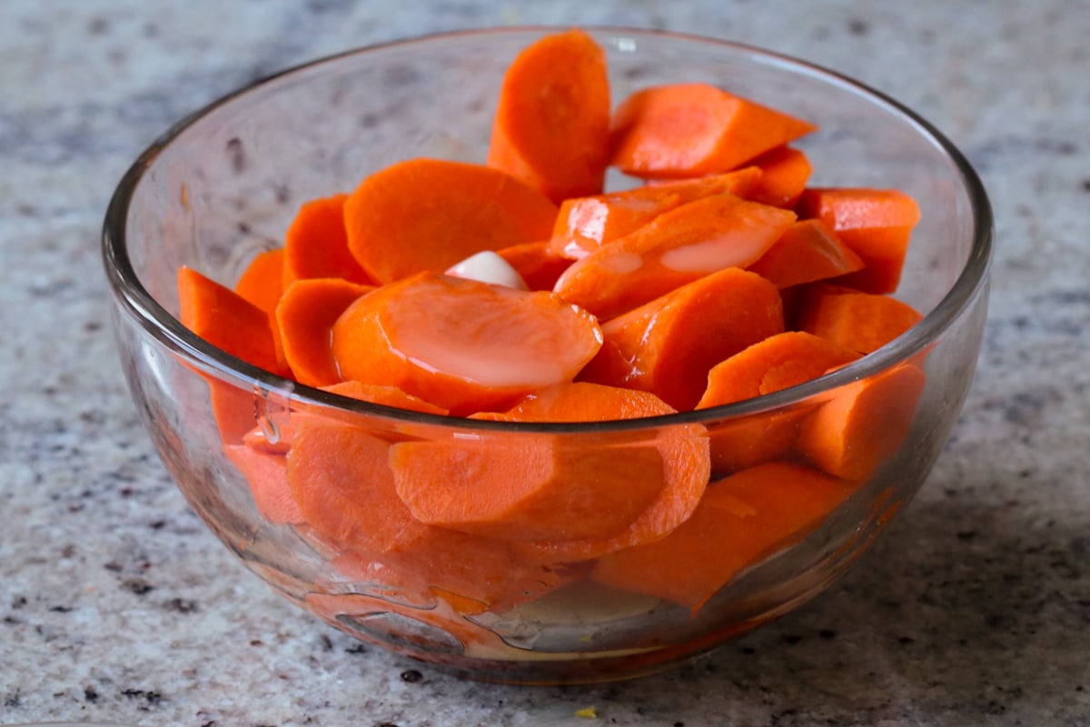 sliced carrots with maple syrup and melted butter in a bowl