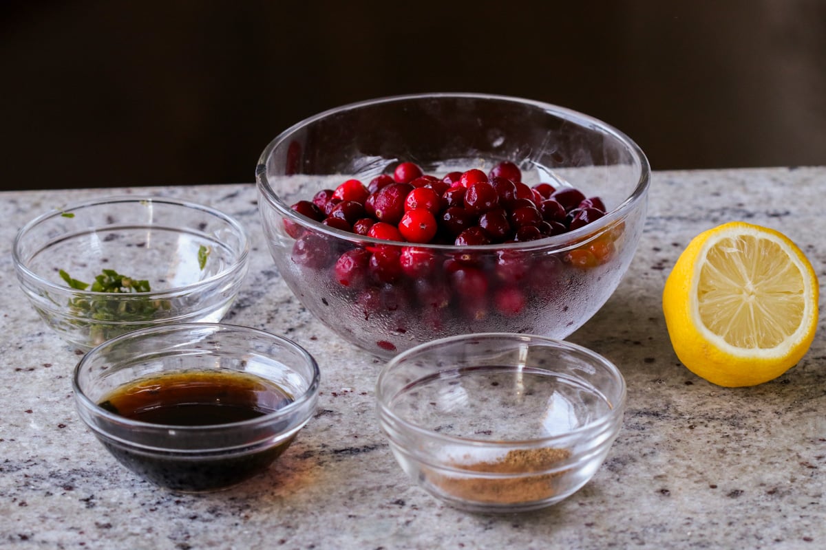 cranberries, maple syrup, and other chutney ingredients in bowls on the counter