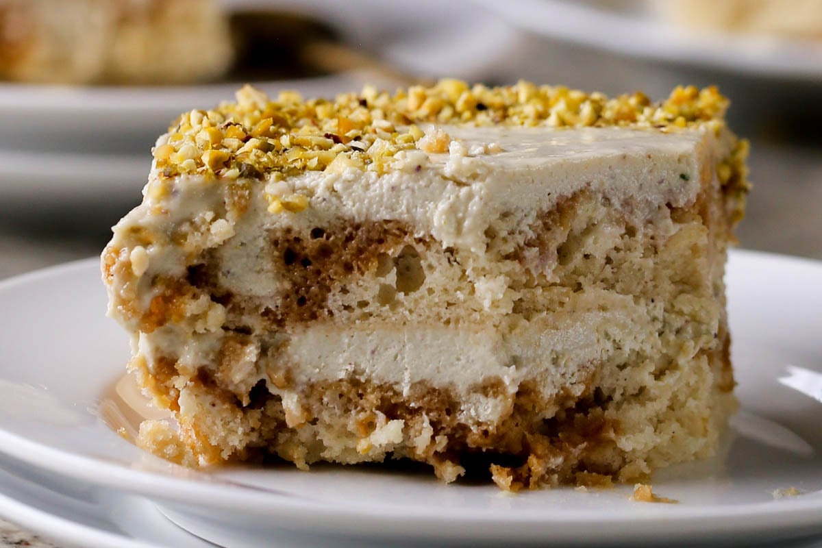 close-up of a slice of Indian tiramisu on a white plate with a bite taken out