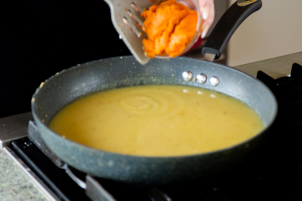 adding pumpkin to the vegan roux in the pan