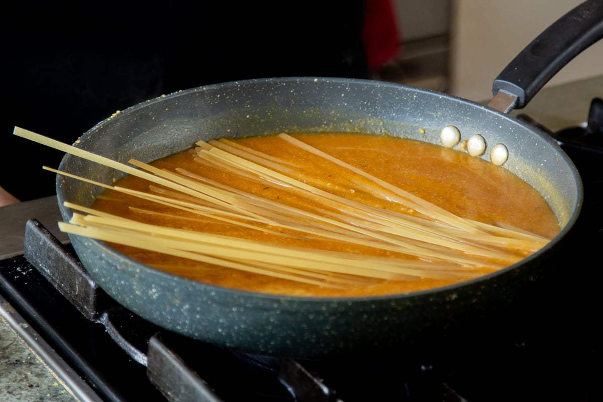 adding pasta to the pumpkin alfredo sauce, before cooking