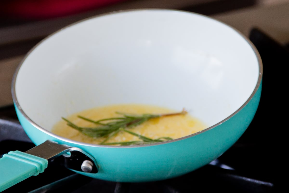 adding butter, garlic, and rosemary to a small pan