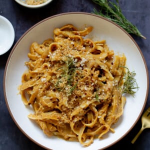 pumpkin alfredo pasta in a bowl topped with the rosemary breadcrumbs