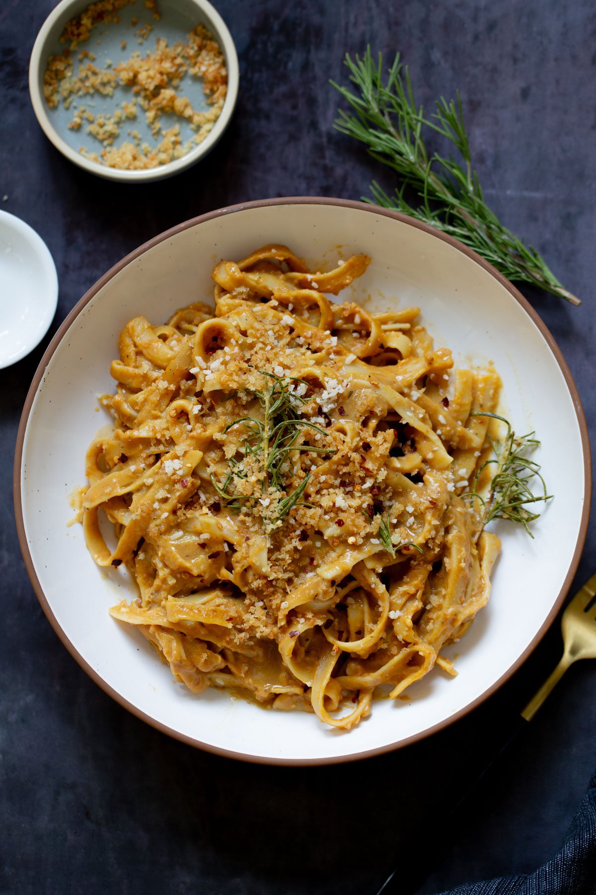 pumpkin alfredo pasta in a bowl topped with the rosemary breadcrumbs