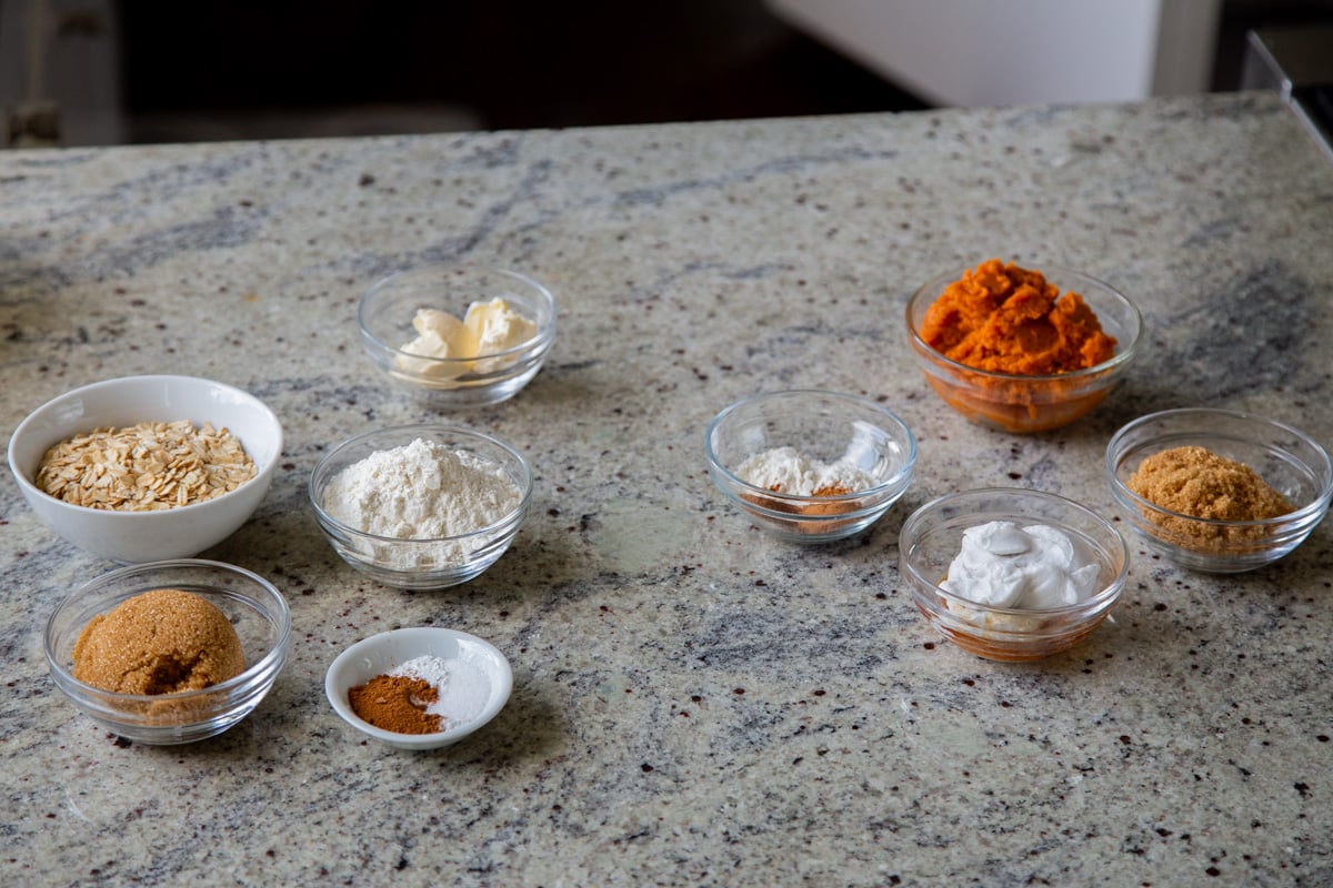 pumpkin puree, flour, oats, and other crisp ingredients in cups on a kitchen counter