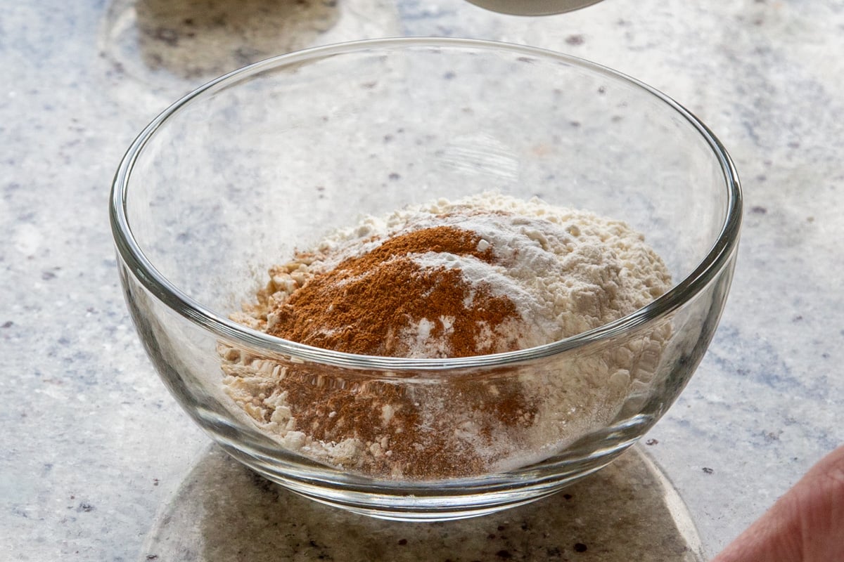 adding flour and spices to the bowl of oats