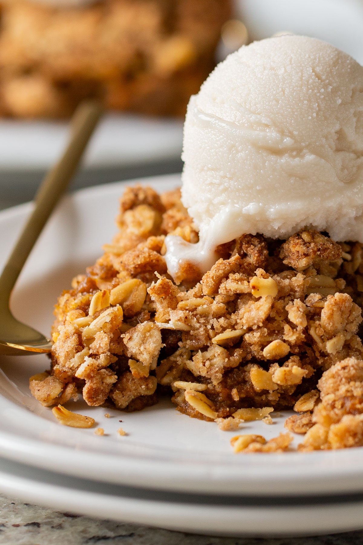 close-up of slice of pumpkin crisp on a white plate with ice cream on top