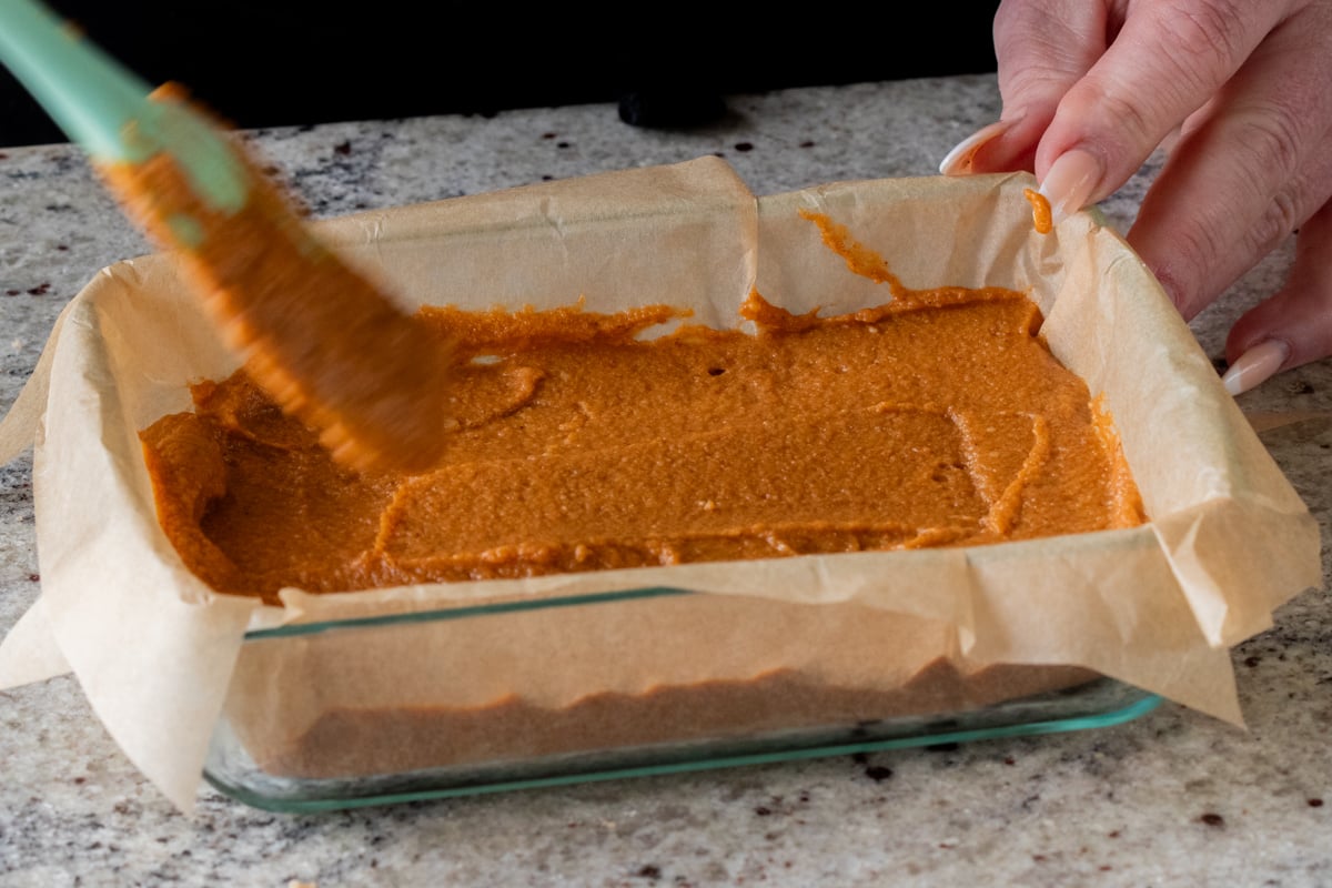 evening out the top of the pumpkin crisp filling in the lined baking pan