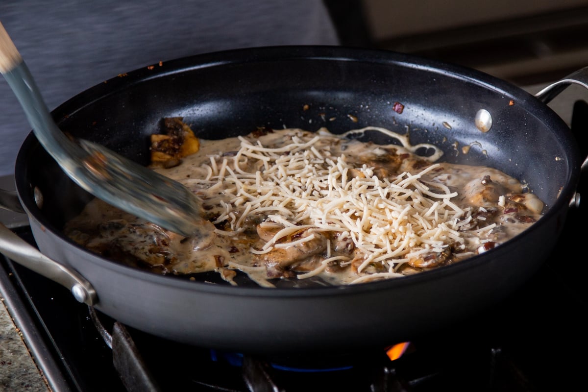 adding vegan parmesan shreds to the cooked mushrooms