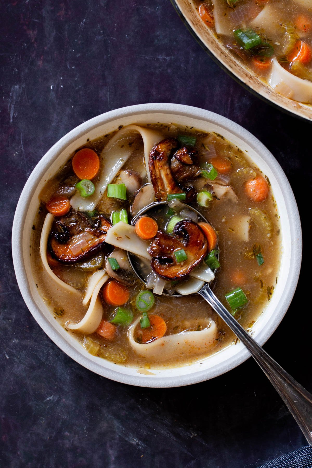 bowl of mushroom noodle soup on a slate table