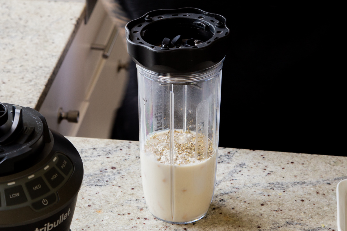 adding miso, flour, and spices to the blender with the cashews and milk