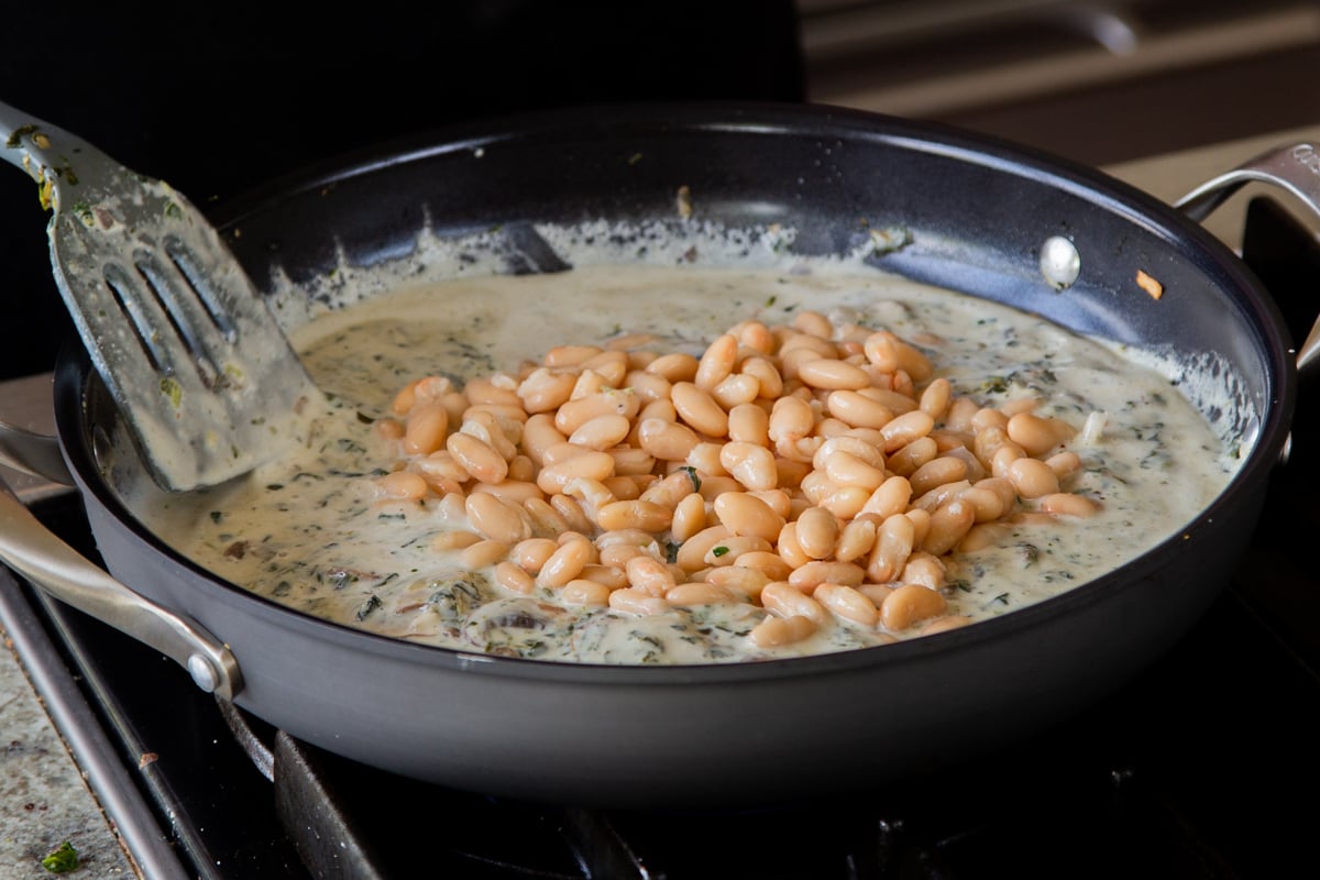 adding white beans to the mushroom alfredo
